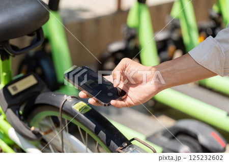 Sustainable Transportation and Technology. A person using a smartphone to access a bike-sharing app for eco-friendly travel. Sustainable Transportation and Technology. A person using a smartphone to access a bike-sharing app for eco-friendly travel. 125232602