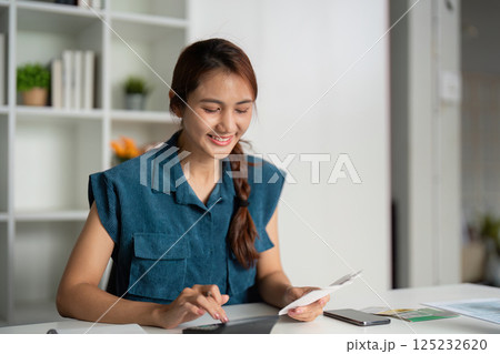 Budgeting and Financial Awareness. A smiling woman exploring her savings and payments on a tablet. Budgeting and Financial Awareness. A smiling woman exploring her savings and payments on a tablet. 125232620