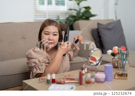 Hair Styling and Beauty. A woman straightening her hair, looking confident in her appearance. 125232674