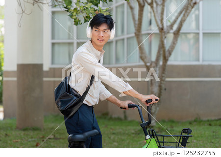 Awareness and Mobility in Urban Landscapes. A person pauses on their bicycle, looking back in a thoughtful manner. Awareness and Mobility in Urban Landscapes. A person pauses on their bicycle, looking back in a thoughtful manner. 125232755