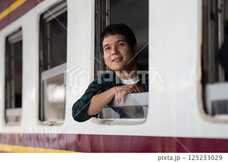 Serenity and Travel Reflections. A young man enjoying a moment at the train window, symbolizing the tranquillity of travel. Serenity and Travel Reflections. A young man enjoying a moment at the train window, symbolizing the tranquillity of travel. 125233029