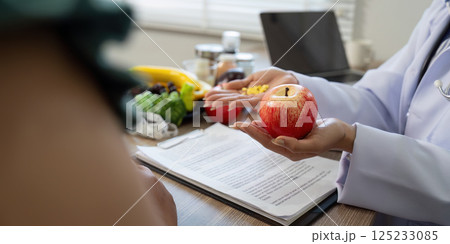 Diet and Measurement. A nutritionist illustrates dietary diversity with a focus on an apple and supplements. 125233085