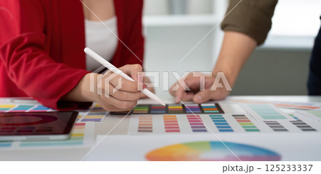 Creative Collaboration and Digital Design. A designer using a tablet in a brainstorming session with color palettes. Creative Collaboration and Digital Design. A designer using a tablet in a brainstorming session with color palettes. 125233337
