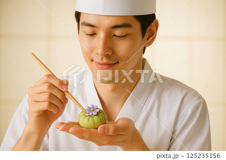 紫の花をあしらう練り切りに微笑む和菓子職人 紫の花をあしらう練り切りに微笑む和菓子職人 125235156