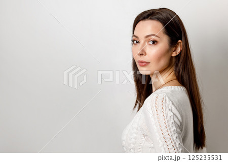 Close-up of a calm, serious, emotionless young woman with brown hair, isolated on a white background. Close-up of a calm, serious, emotionless young woman with brown hair, isolated on a white background. 125235531