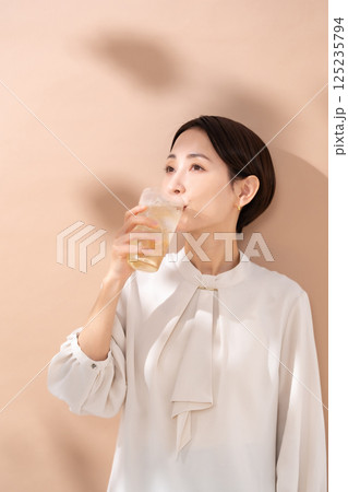 ハイボールを飲む女性　日差し 125235794