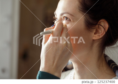 Professional female makeup artist carefully applies makeup to a client's face in the salon. 125237400