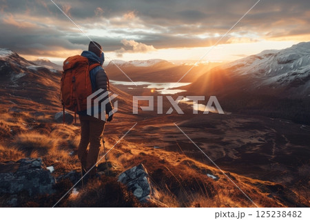 Hiker Admiring Golden Sunrise Over Mountain Valley 125238482