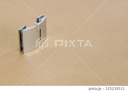 chrome glass hinge on a brown table chrome glass hinge on a brown table 125238511