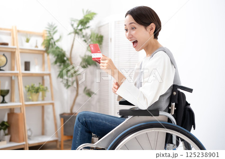 通帳を見て喜ぶ車椅子の女性 通帳を見て喜ぶ車椅子の女性 125238901