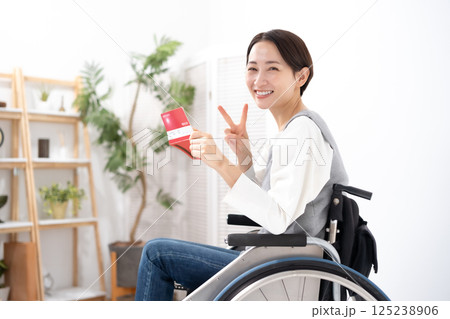 通帳を見て喜ぶ車椅子の女性 125238906