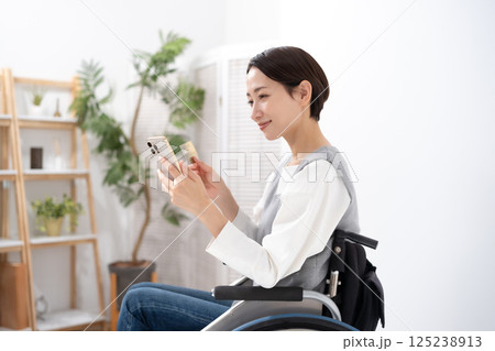 スマホとカードを持つ車椅子の女性 125238913