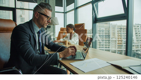 Businesspeople working on laptops in office 125240146