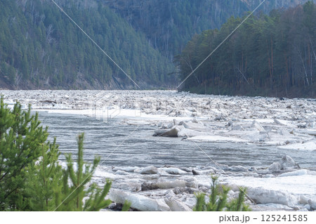 Spring melting of ice, Ice drift on the Siberian Mana River. Piles and congestion of melting ice floes. View of the river in the middle of the forest during the day. Spring melting of ice, Ice drift on the Siberian Mana River. Piles and congestion of melting ice floes. View of the river in the middle of the forest during the day. 125241585