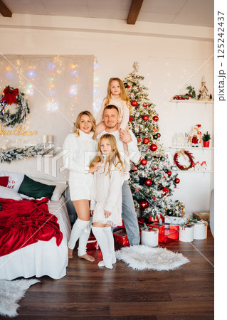 A beautiful and happy family at the Christmas tree at home A beautiful and happy family at the Christmas tree at home 125242437