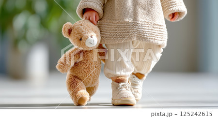 toddler walking indoors holding teddy bear, wearing cozy beige clothing toddler walking indoors holding teddy bear, wearing cozy beige clothing 125242615