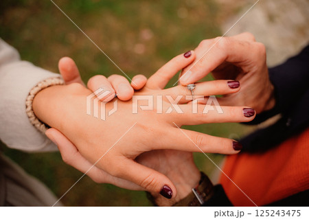 Man places engagement ring on his beloved's hand Man places engagement ring on his beloved's hand 125243475