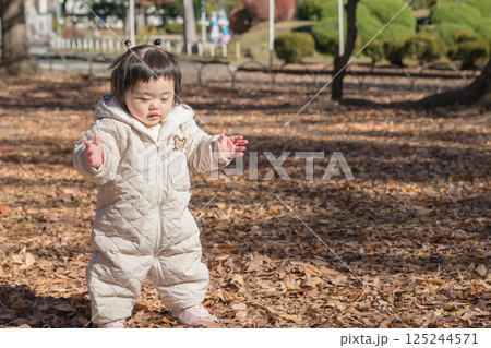 【冬の落ち葉がある公園で遊ぶ1歳児　立つ】 125244571