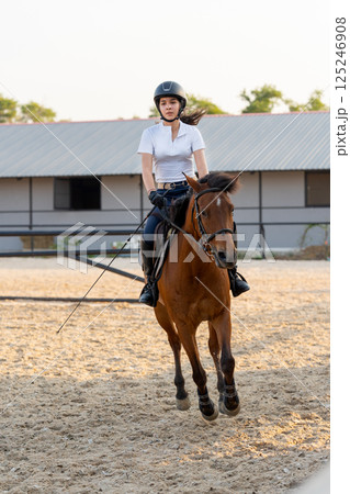 Vertical image of teen girl control horse to run around in the arena for training and practice before the competition. Vertical image of teen girl control horse to run around in the arena for training and practice before the competition. 125246908