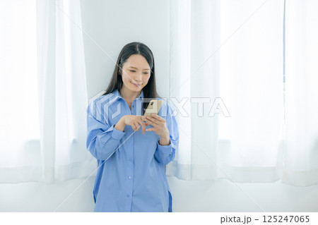 窓際でスマホを操作するミドル女性 窓際でスマホを操作するミドル女性 125247065