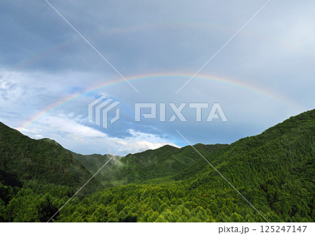 初夏の雨上がり、新緑の山の彼方に二重の虹が現れた。空にかかる谷の架け橋が印象的で綺麗だ。 125247147