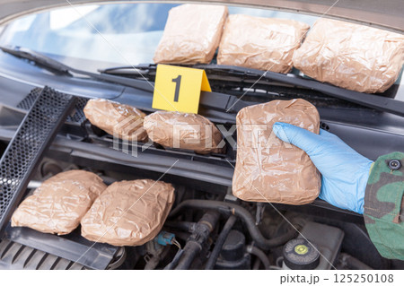 Narcotic smuggling: Hidden drug packages discovered in engine compartment of a car 125250108