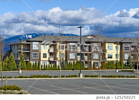 Low rise residential building with big parking lot in front on mountain background 125250225