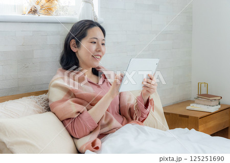 ベッドでタブレットを見る女性 ベッドでタブレットを見る女性 125251690