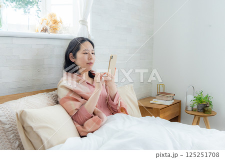 ベッドでスマホを見る女性 ベッドでスマホを見る女性 125251708