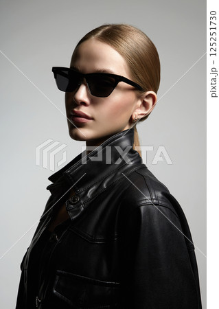 pretty blond girl in black glasses and leather coat 125251730