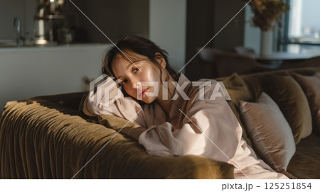 Serene Young Woman in Pink Robe Relaxing on Mustard Couch 125251854