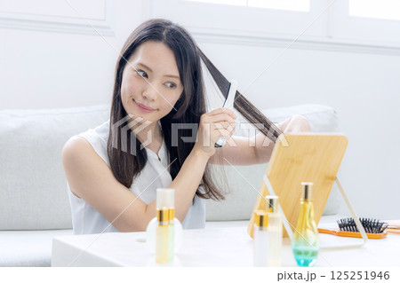 ヘアアイロンをかけるミドル女性 125251946
