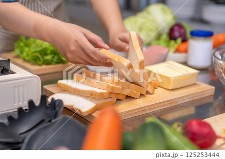 Close-up hands of a Young Female Chef Preparing a Sandwich in a Professional Kitchen 125253444