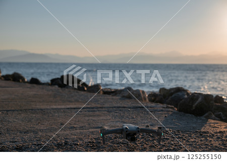 A drone is sitting on the beach near the water 125255150
