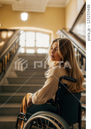 Young Woman in Wheelchair Sits on Staircase in a Beautifully Lit Building During the Day 125255486