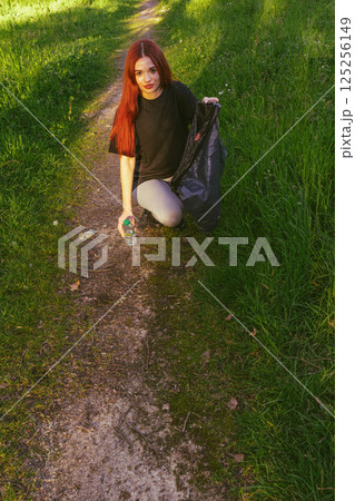 Young man picking up trash in nature 125256149