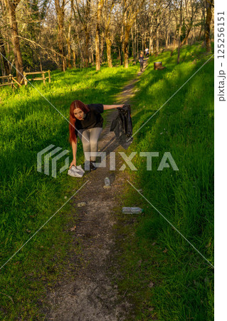 Young man picking up trash in nature 125256151