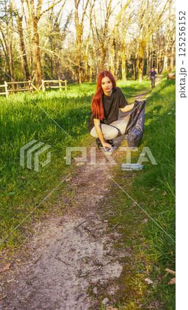 Young man picking up trash in nature 125256152