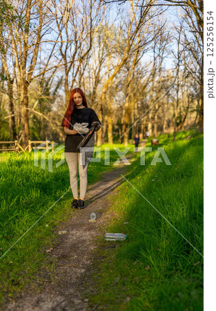 Young man picking up trash in nature 125256154