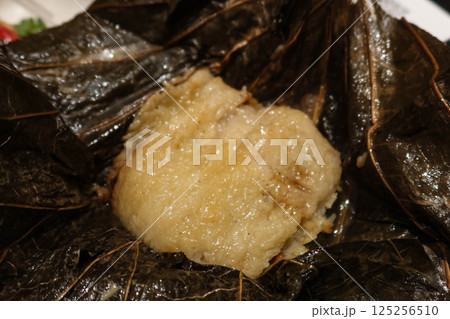 close up of Hong Kong style traditional Chinese rice dumplings in pyramid shaped and are stuffed with savoury ingredients, wrapped in bamboo leaves 125256510