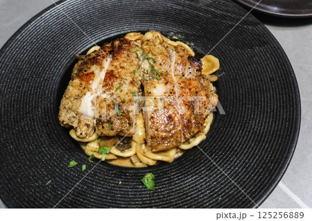 close up of grilled chicken fillet with Orecchiette pasta mixed with a creamy sauce, mushroom and fresh herbs 125256889