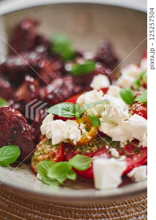 Fried chicken liver and tomato and feta cheese salad garnished with basil 125257504