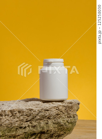 White plastic medicine jar on stone, yellow background. Mock up White plastic medicine jar on stone, yellow background. Mock up 125258030