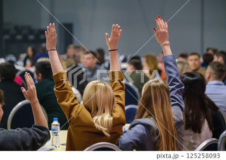 Audience engagement at event with attendees raising hands in discussion Audience engagement at event with attendees raising hands in discussion 125258093