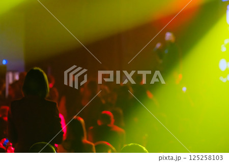 Blurred silhouettes of people under colorful lights in a concert scene 125258103