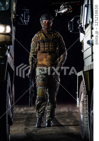 A soldier marching through the dark of night, accompanied by two military trucks, as he embarks on a perilous military mission, embodying the unwavering determination, teamwork, and preparedness A soldier marching through the dark of night, accompanied by two military trucks, as he embarks on a perilous military mission, embodying the unwavering determination, teamwork, and preparedness 125258630