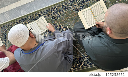 Mecca, Saudi Arabia - May 2, 2024: Young man, Hajj and Umrah pilgrim sitting and reading Quran in Masjidil Haram, Great Mosque in Makkah, Saudi Arabia. Hajj 2024. 125258651