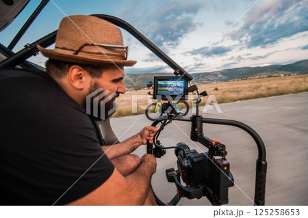 A videographer recording a triathlete riding his bike preparing for an upcoming marathon.Athlete's physical endurance and the dedication required to succeed in the sport. 125258653