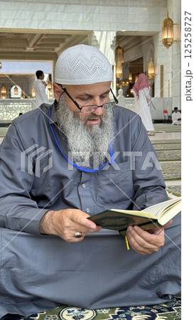 Mecca, Saudi Arabia - May 2, 2024: Young man, Hajj and Umrah pilgrim sitting and reading Quran in Masjidil Haram, Great Mosque in Makkah, Saudi Arabia. Hajj 2024. Mecca, Saudi Arabia - May 2, 2024: Young man, Hajj and Umrah pilgrim sitting and reading Quran in Masjidil Haram, Great Mosque in Makkah, Saudi Arabia. Hajj 2024. 125258727