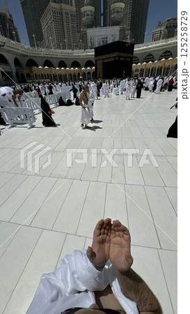 A bald man poses for a photo in front of the Kaaba at noon after performing Umrah at Masjid al-Haram, Mecca. A sacred Islamic pilgrimage in the heart of the holy mosque under the bright sunlight. A bald man poses for a photo in front of the Kaaba at noon after performing Umrah at Masjid al-Haram, Mecca. A sacred Islamic pilgrimage in the heart of the holy mosque under the bright sunlight. 125258729